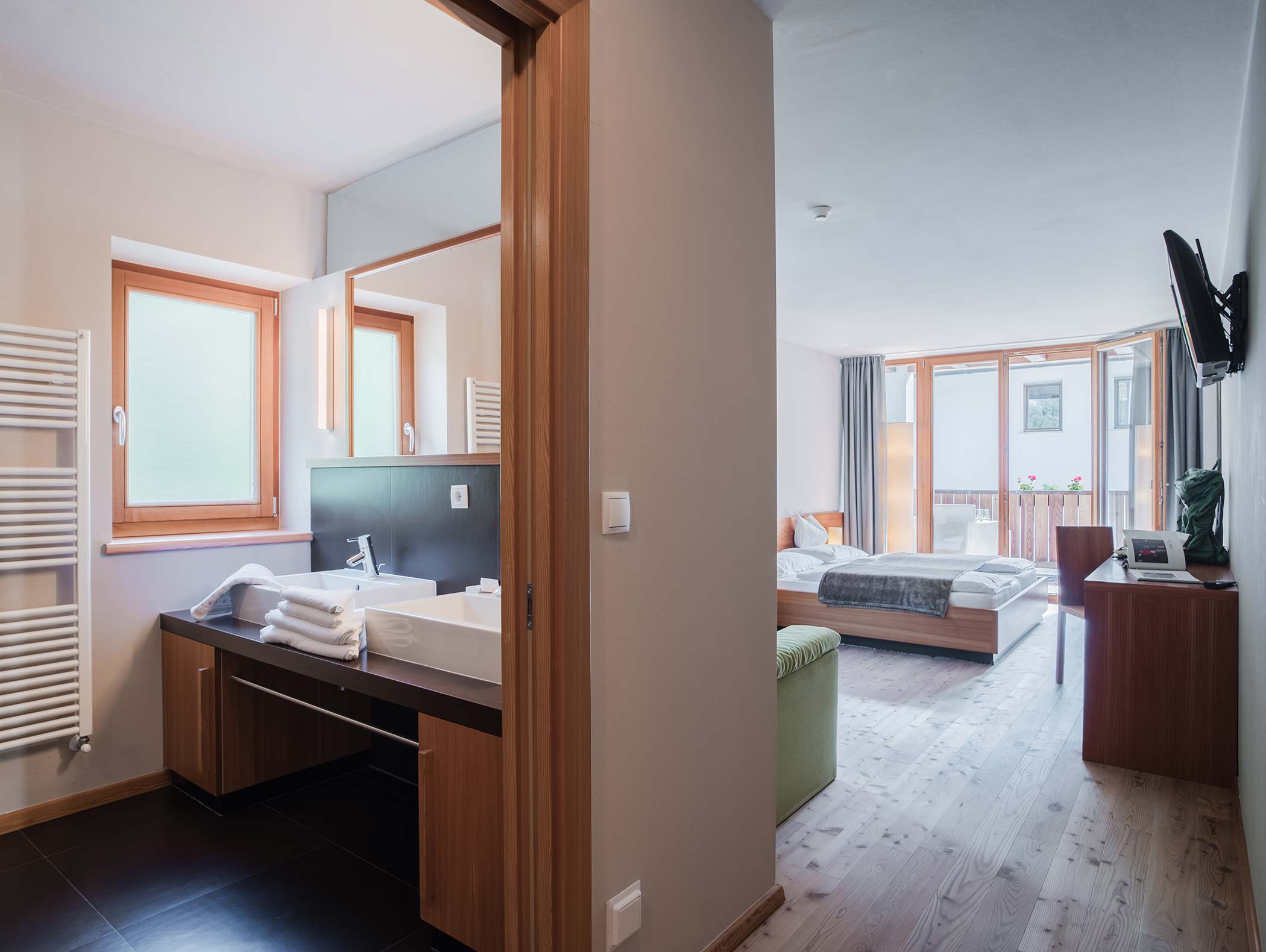 Moderna camera d'albergo con letto matrimoniale, balcone, TV e bagno adiacente con lavandino e asciugamani. - Hotel Moosmair