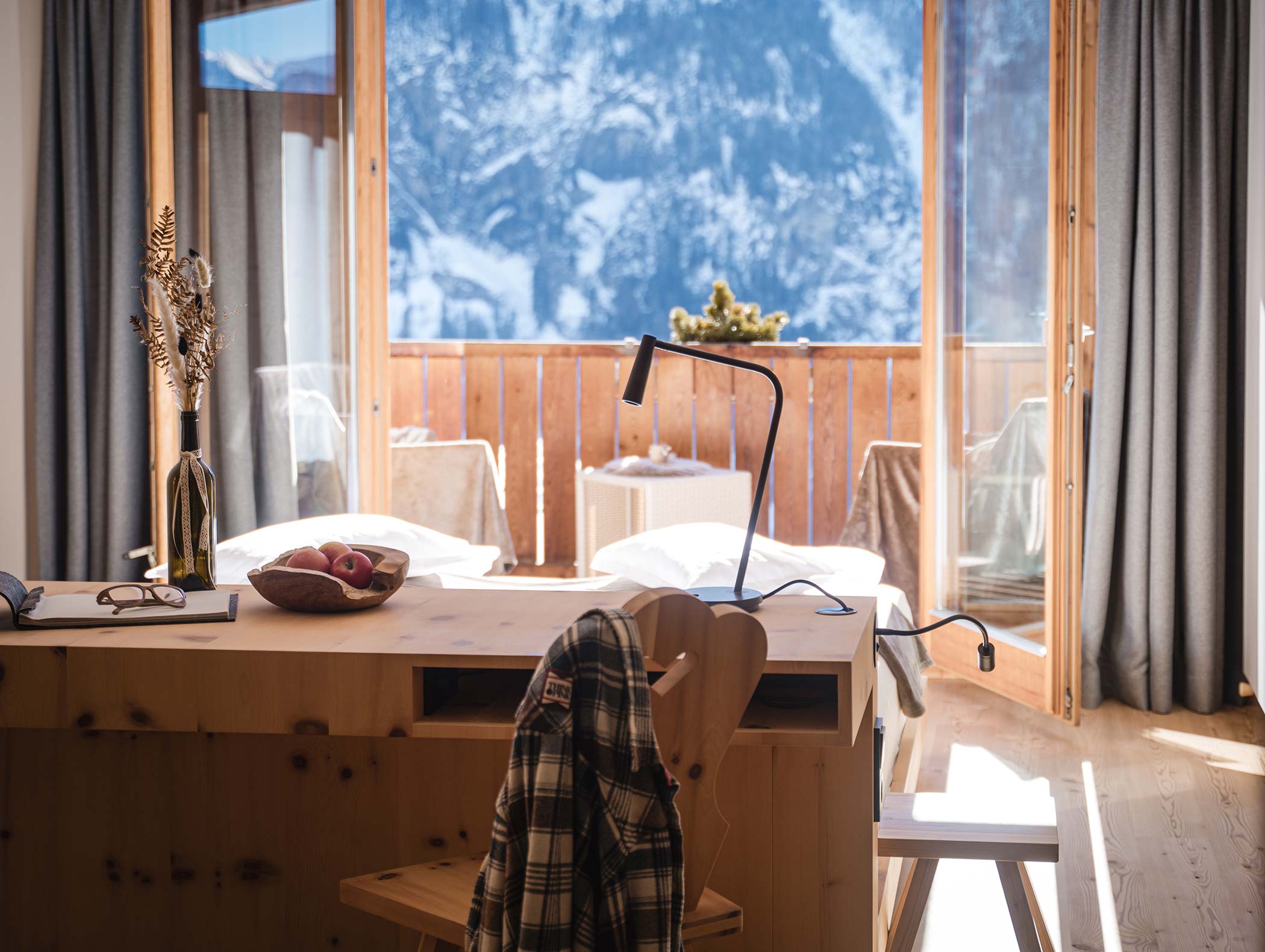 Accogliente camera in legno con vista sulle montagne, letto, scrivania e balcone in una giornata di sole. - Hotel Moosmair