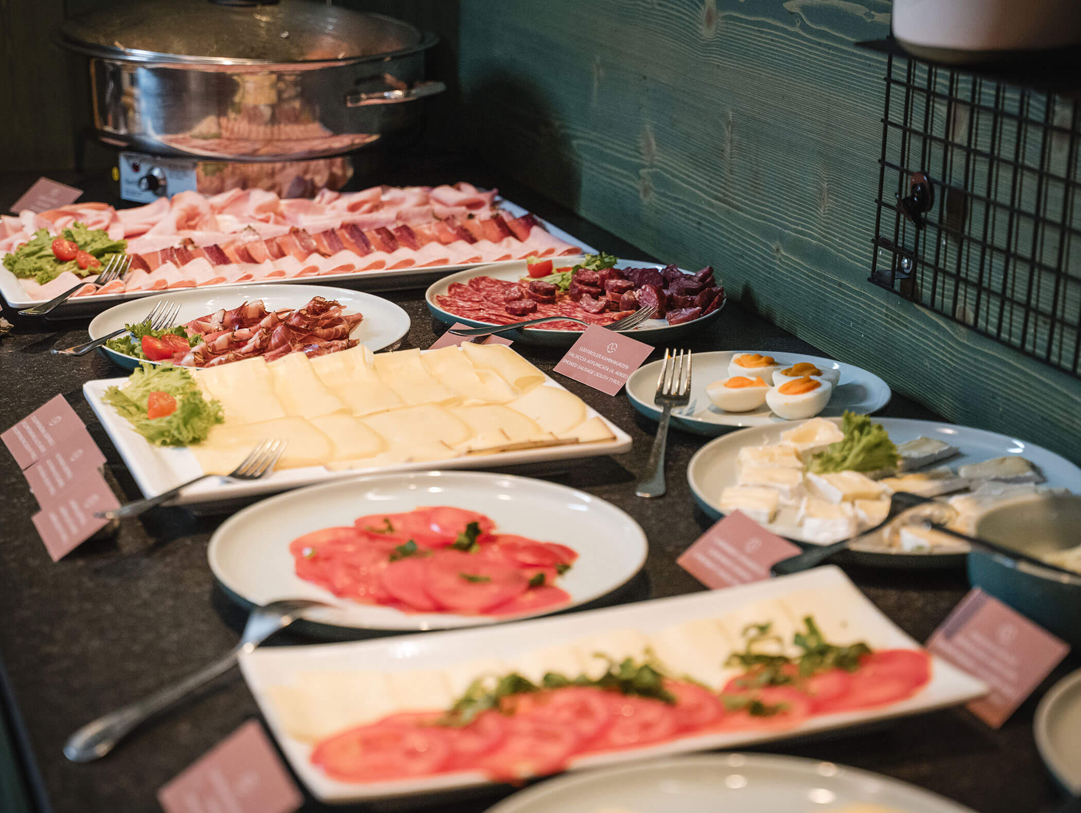 Buffet-Tisch mit Aufschnitt, Käse, Tomaten, gekochten Eiern und Etiketten für jeden Artikel. - Hotel Moosmair