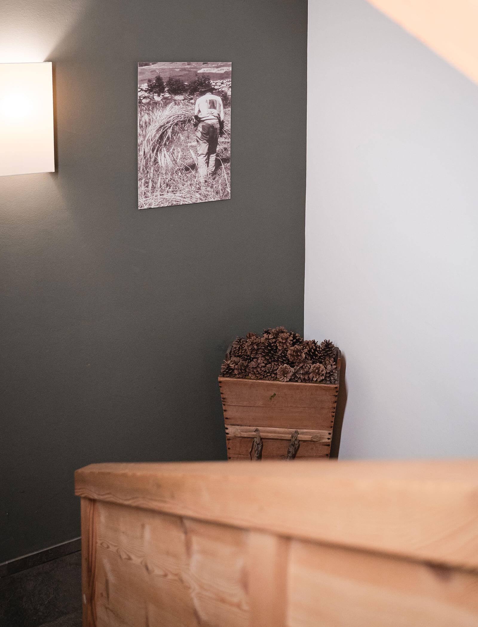 Una scala di legno con un cesto di pigne e una foto in bianco e nero sulla parete sovrastante. - Hotel Moosmair