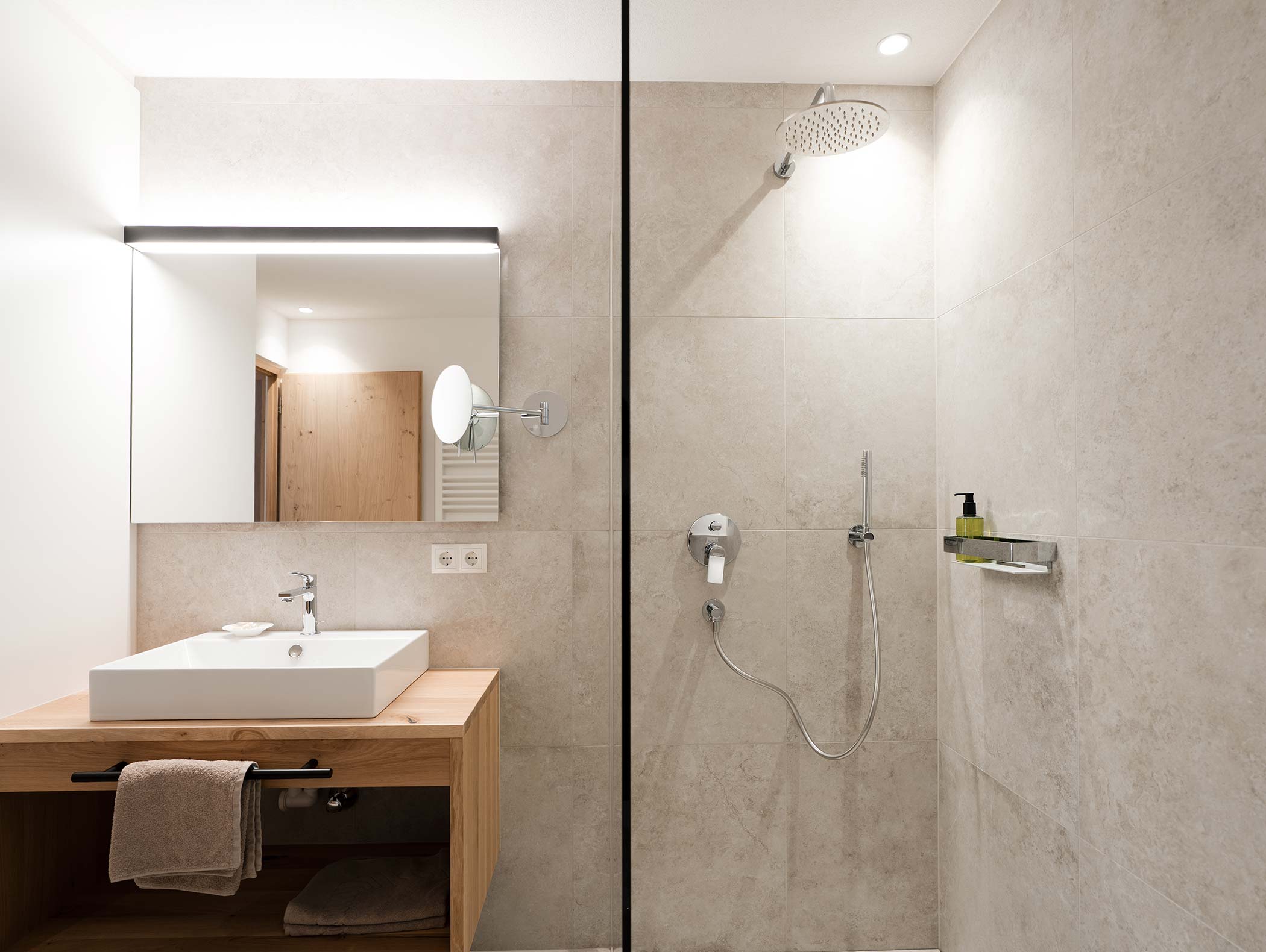 Bagno moderno con vanità in legno, lavabo quadrato, grande specchio e cabina doccia con soffione a pioggia. - Hotel Moosmair