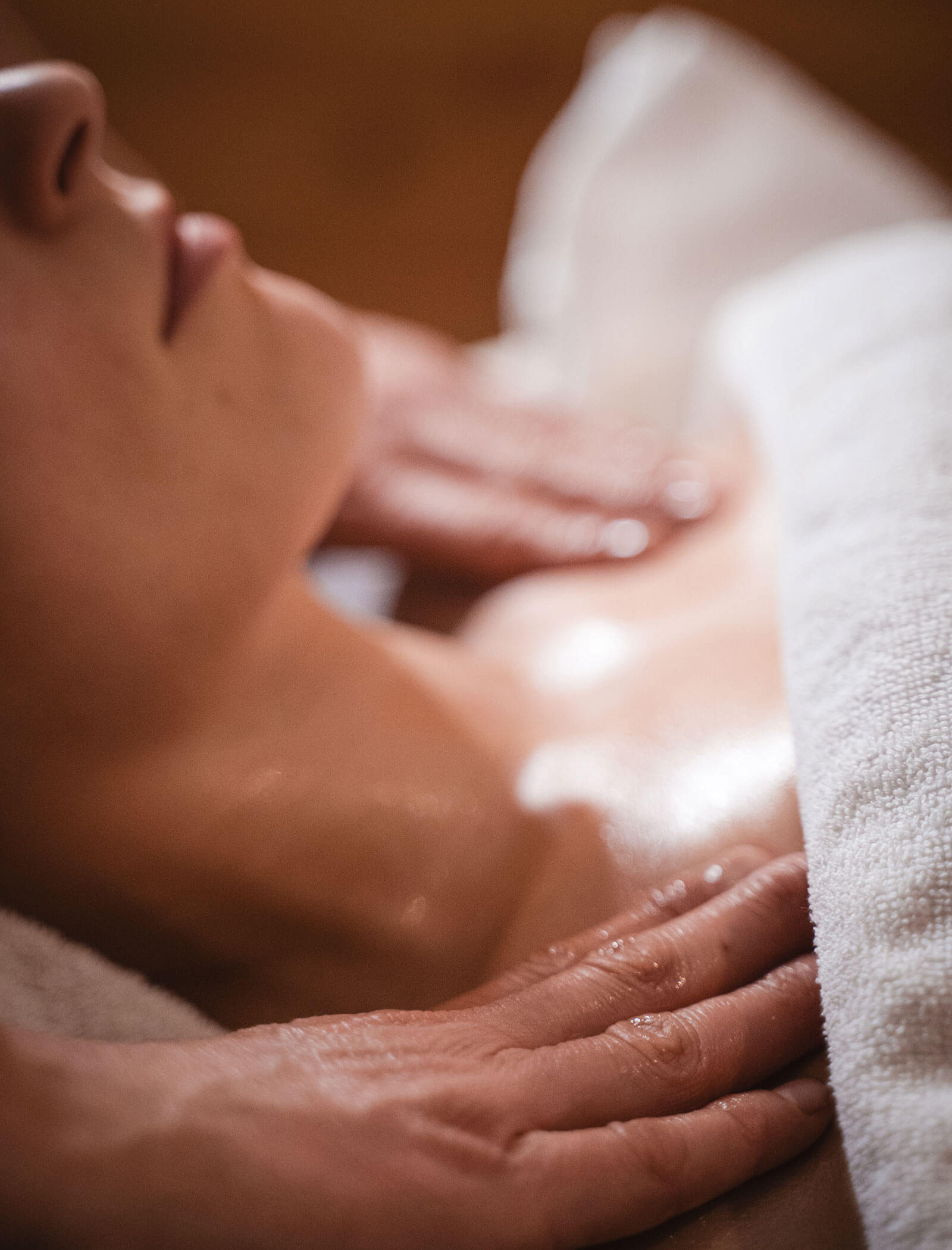 Nahaufnahme einer Person, die eine entspannende Brust- und Schultermassage erhält, während ein weißes Handtuch über sie gelegt wird. - Hotel Moosmair